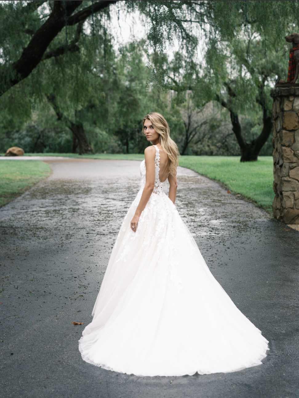 Bridal portrait by Joseph West, with a white gown against green trees and a quiet garden path.